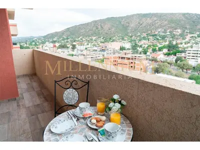 a table with cups and plates of food on a balcony at Departamento de categoria en Villa Carlos Paz in Villa Carlos Paz