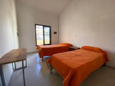 a room with two beds and a table and a window at casa con pileta cerca de pekos y carlos paz in Villa Carlos Paz