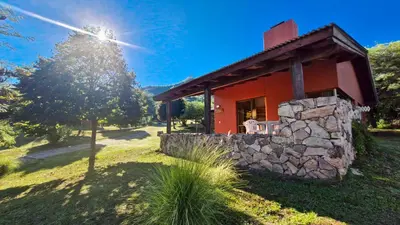 a small red house with a stone wall at Cabañas Balcon al Champaqui in Villa General Belgrano