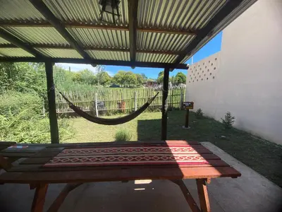 a porch with a hammock and a patio with a fence at Casitas Del Champaqui in Villa Yacanto