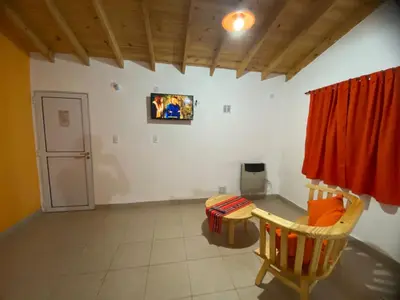 a room with a table and a tv on the wall at Casitas Del Champaqui in Villa Yacanto