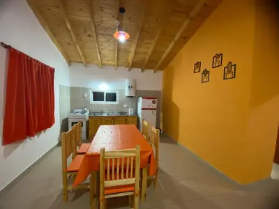a dining room with a table and a kitchen at Casitas Del Champaqui in Villa Yacanto