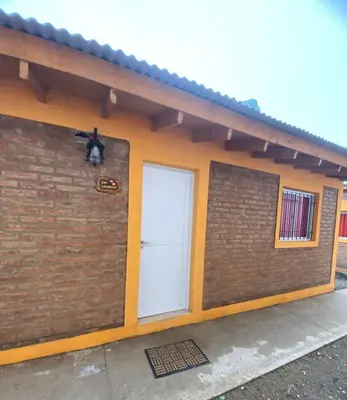 a small brick building with a white door at Casitas Del Champaqui in Villa Yacanto