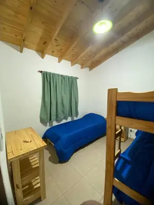 a bedroom with two bunk beds and a table at Casitas Del Champaqui in Villa Yacanto