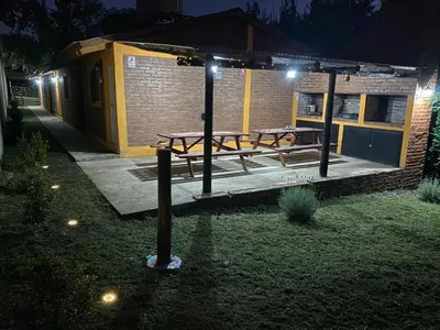a patio with two picnic tables on it at night at Casitas del Champaqui in Villa Yacanto