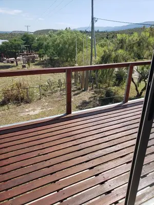 a wooden balcony with a view of a field at Miradores del Dique in San Francisco del Monte de Oro