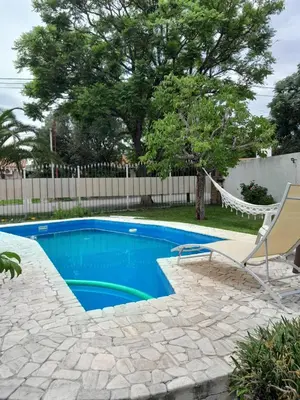 a swimming pool with a hammock and a chair at Departamento Carolina in Villa Carlos Paz