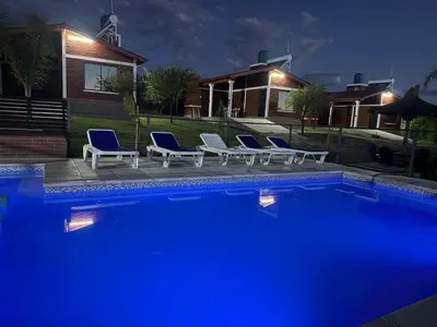 a group of chairs sitting next to a pool at night at Cabañas AdamiS 5 in Villa Cura Brochero