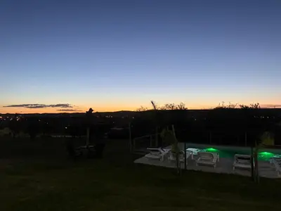 a sunset over a yard with chairs and a pool at Cabañas AdamiS 5 in Villa Cura Brochero