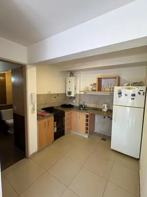 a kitchen with a white refrigerator and wooden cabinets at Cañada 12 depto 1 dormitorio pax 3 in Cordoba