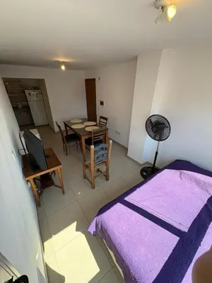 a room with a bed and a table and a kitchen at Cañada 12 depto 1 dormitorio pax 3 in Cordoba