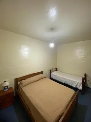 a bedroom with two beds and a night stand with a lamp at Hosteria las Palmeras in Mina Clavero