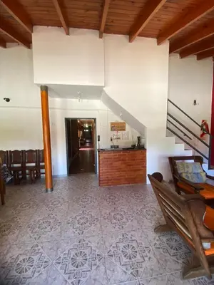 a living room with a staircase and a table and chairs at Hosteria las Palmeras in Mina Clavero