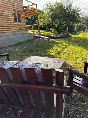 a wooden bench sitting in a yard next to a building at Alojamiento en san clemente Pampa y Rio cabaña Lihuel in Santa María