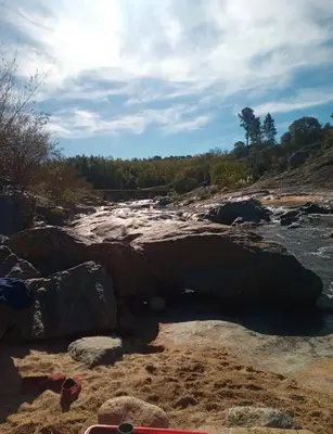 a view of a river with rocks on the shore at Alojamiento en san clemente Pampa y Rio cabaña Lihuel in Santa María