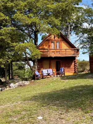 a log cabin with two chairs in front of it at Alojamiento en san clemente Pampa y Rio cabaña Lihuel in Santa María
