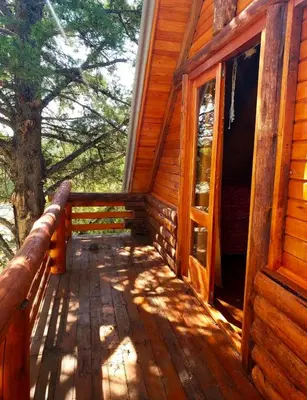 a porch of a log cabin with trees in the background at Alojamiento en san clemente Pampa y Rio cabaña Lihuel in Santa María