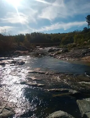 a river with rocks and the sun shining at Alojamiento en san clemente Pampa y Rio cabaña Lihuel in Santa María