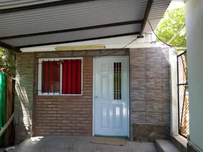 a brick house with a white door and a red curtain at Lo de Alicia in Santa Rosa de Calamuchita