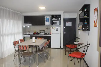 a kitchen with a table and chairs and a refrigerator at Excelente departamento moderno con pileta in Villa Carlos Paz