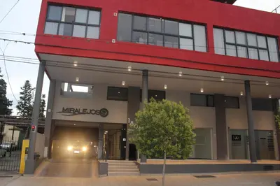 a large red and white building with a tree in front at Excelente departamento moderno con pileta in Villa Carlos Paz