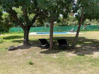 two chairs sitting under two trees in a park at Serena in Villa de Las Rosas
