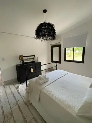 a bedroom with a white bed and a chandelier at Serena in Villa de Las Rosas