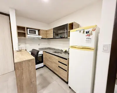 a kitchen with a white refrigerator and wooden cabinets at Paseo Cibeles in Villa Carlos Paz