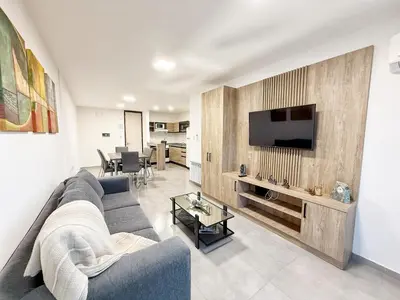 a living room with a gray couch and a tv at Paseo Cibeles in Villa Carlos Paz