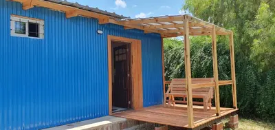 a blue shed with a wooden deck with a swing at Complejo Canto de los Pájaros in Villa Parque Siquiman
