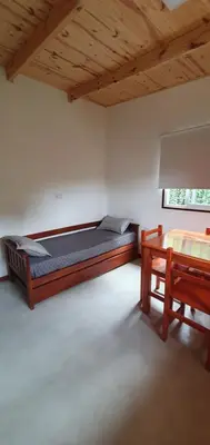 a bedroom with a bed and a table in it at Complejo Canto de los Pájaros in Villa Parque Siquiman