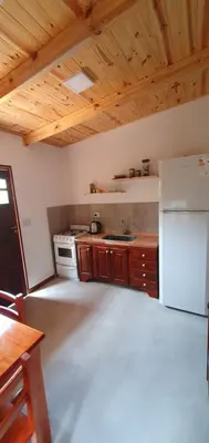 a kitchen with a white refrigerator and wooden cabinets at Complejo Canto de los Pájaros in Villa Parque Siquiman