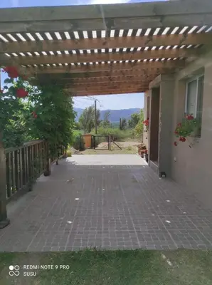 an outdoor patio with a wooden pergola and a house at Casa El ALto 1 in Villa General Belgrano