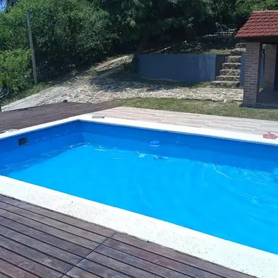 a large blue swimming pool with a wooden deck at La Calandria in Villa Serranita