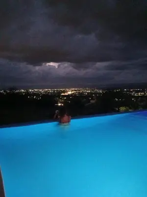 a person sitting at the edge of a swimming pool at Cabaña La Reserva in San Roque