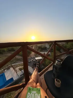 a person laying on a balcony watching the sunset at Cabaña La Reserva in San Roque