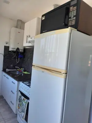 a kitchen with a refrigerator with a microwave on top of it at Fabiana Torres in Villa Carlos Paz