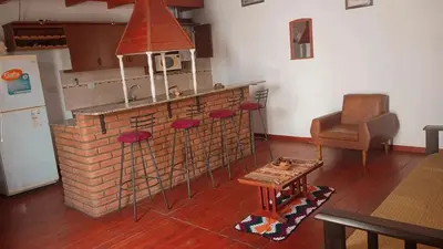 a kitchen with a brick counter with stools and a table at Departamento Villa Dolores in San Javier
