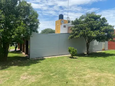 a house with a fence and two trees in a yard at Complejo los lirios in Villa Los Aromos