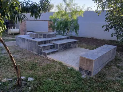 a stone bench in a yard with a fire pit at Complejo los lirios in Villa Los Aromos