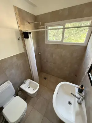 a bathroom with a white toilet and a sink at Departamento Lago Los Molinos in Villa Ciudad de America