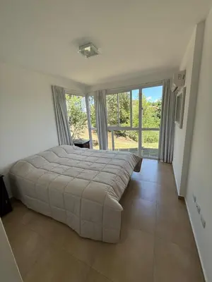 a large bed in a bedroom with a large window at Departamento Lago Los Molinos in Villa Ciudad de America