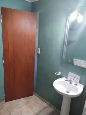 a bathroom with a sink and a wooden door at Cabaña Villa del Dique, Calamuchita in Villa del Dique