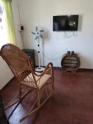 a room with a chair and a fan and a television at Cabaña Villa del Dique, Calamuchita in Villa del Dique