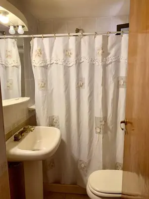 a bathroom with a white shower curtain and a sink at casa vista al lago in Villa Carlos Paz