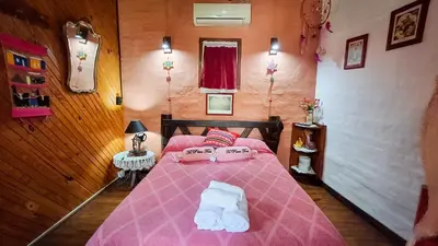 a bedroom with a pink bed with towels on it at Cabaña Té para Tres en Merlo San Luis in Merlo