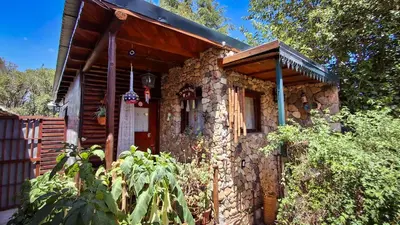 a stone house with a red door at Cabaña Té para Tres en Merlo San Luis in Merlo