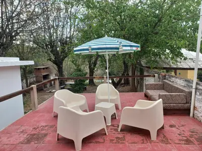 a patio with white chairs and an umbrella at Yuncasuma in Tanti