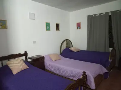 three beds in a room with purple sheets at Yuncasuma in Tanti