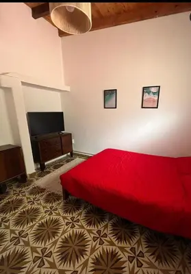 a bedroom with a red bed and a flat screen tv at Yuncasuma in Tanti